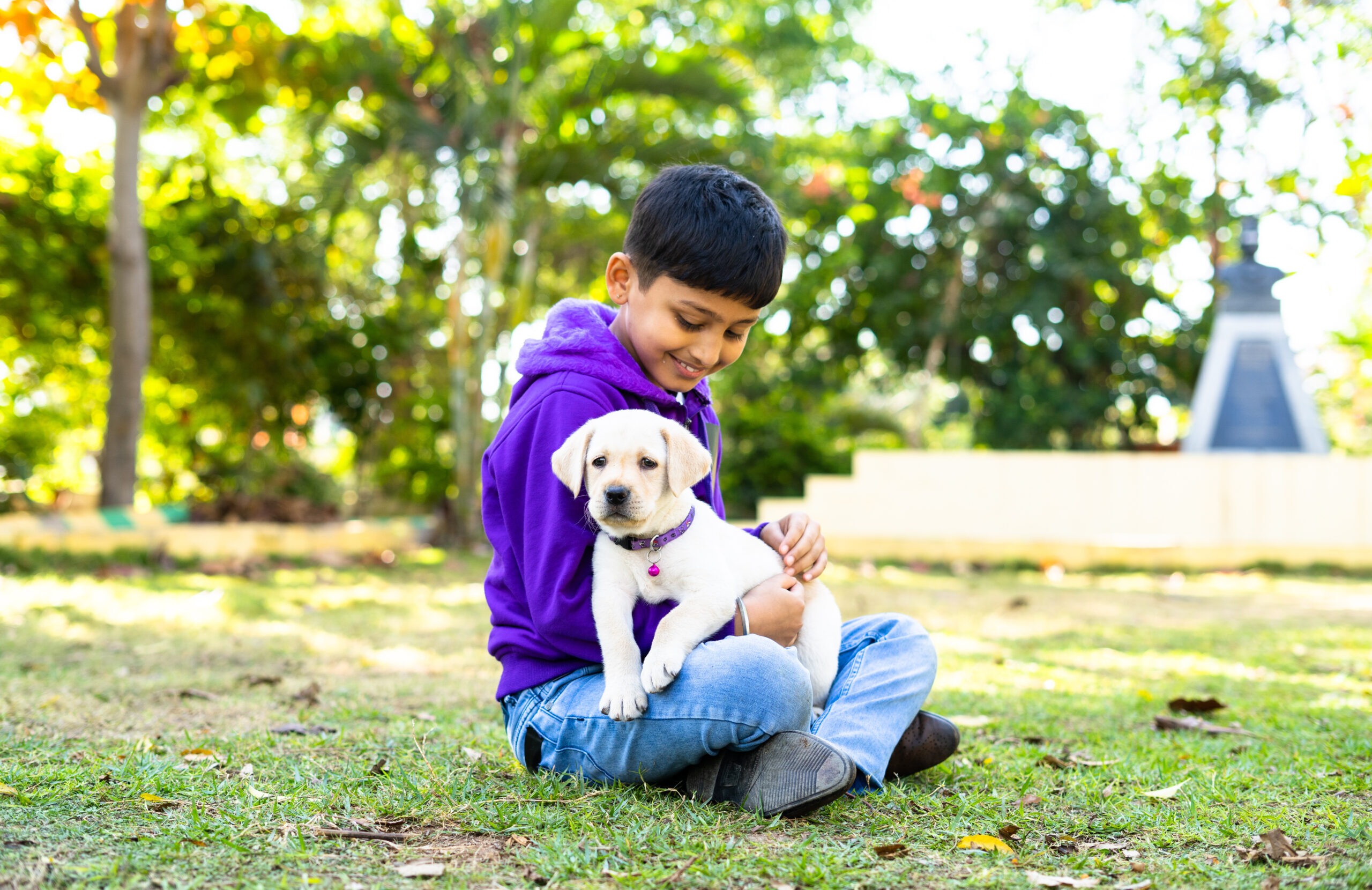 Young-Indian-Kid-playing-by-holding-puppy-dog-at-park-for-a-blog-on-how-to-take-care-of-pet-animals-scaled